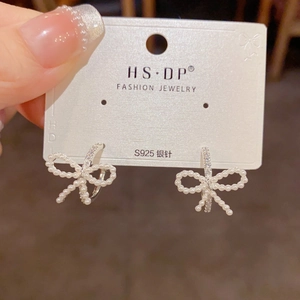 Primer plano de pendientes de lazo con perlas, agujas de plata S925 y micro diamantes