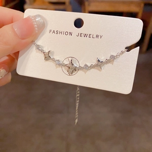Detailed shot of silver star bracelet with zircon charms on a fashion display card