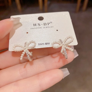 Detalle de pendientes de lazo plateados con perlas y cristales y agujas de plata S925