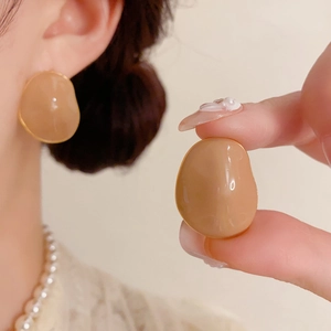 Close-up of irregular caramel enamel earrings with gold-plated edges on a model