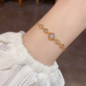 Nahaufnahme eines vergoldeten Armbands mit fünf Zirkonia-Steinen am Handgelenk des Models