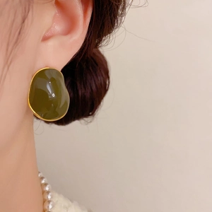 Close-up of irregular olive green enamel stud earring with gold edge on model ear
