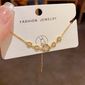 Nahaufnahme eines goldenen Armbands mit fünf klaren Steinen auf einer Schmuckkarte