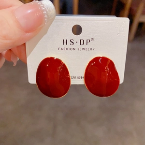 Macro detail of irregular deep red enamel studs with gold trim on a 925 silver needle card