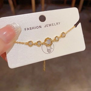 Detail eines goldenen geometrischen Armbands mit funkelnden Zirkonia auf Metallgliedern
