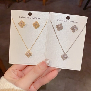Détail de parures trèfle colliers et boucles d'oreilles en finitions doré et argenté