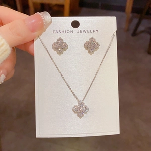 Détail de l'ensemble collier et boucles d'oreilles trèfle en zircon sur carte de présentation