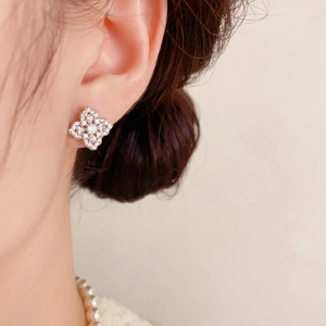 Gros plan de boucles d'oreilles trèfle en zircon étincelant portées pour un style chic
