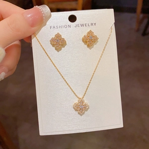 Détail d'un ensemble de bijoux trèfle doré avec zircons brillants sur carte de support