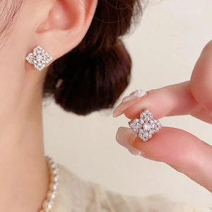 Détail de boucles d'oreilles trèfle en argent avec oxydes de zirconium sur un mannequin