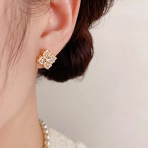 Gros plan de petites boucles d'oreilles trèfle doré serties de zircons brillants