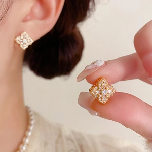 Détail des boucles d'oreilles fleur à quatre feuilles en zircon et fini doré chic