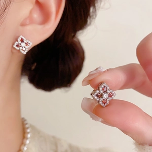 Gros plan de boucles d'oreilles fleur à quatre pétales avec gemmes rouges et zircons brillants