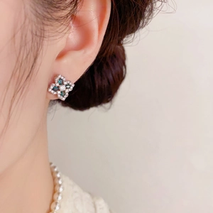 Détail des boucles d'oreilles trèfle en argent avec pierres vertes et micro-diamants