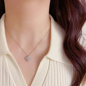 Gros plan d'un collier fleur à quatre feuilles en argent avec zircons porté par un modèle