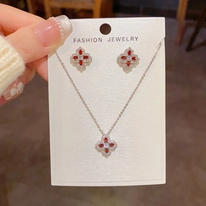 Gros plan sur parure collier et boucles d'oreilles en zircon rouge et métal argenté brillant