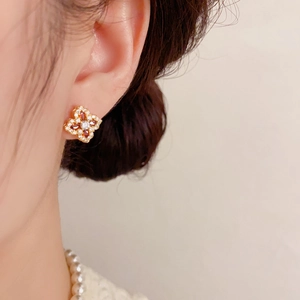 Gros plan de boucles d'oreilles trèfle élégantes avec zircons rouges et blancs sur modèle