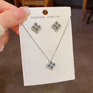 Gros plan détaillé du collier trèfle en zircon brillant et des boucles d'oreilles vertes