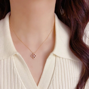 Vue détaillée du collier trèfle doré avec zircons rouges et blancs porté par un mannequin