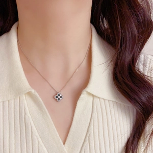 Détail d'un collier trèfle argenté avec zircons bleus et blancs sur un mannequin