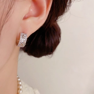 Boucles d'oreilles étoile scintillantes serties de zircones portées avec collier de perles