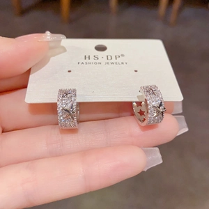 Gros plan de boucles d'oreilles créoles étoiles en argent avec zircons sur leur support