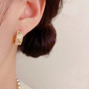 Gros plan d'une créole dorée avec élément étoile et zircons sur l'oreille du mannequin