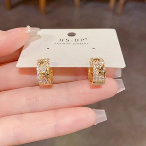 Gros plan sur des boucles d'oreilles étoiles dorées serties de strass sur carte bijou