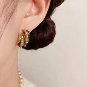 Detail von französischen Vintage C-Ohrringen in Gold mit bernsteinfarbenen Perlen am Modell