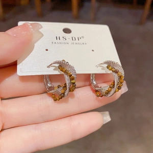 Detail von gewebten Silberohrringen mit Tigerauge-Perlen im Boho-Stil