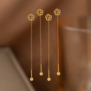 Detail of elegant gold rose earrings with long tassels and delicate sphere pendants