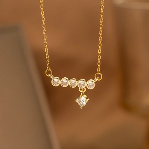 Macro shot of gold necklace with six white cubic zirconia stones in wheat spike design
