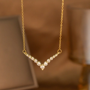 Macro shot of V-shaped gold necklace pendant with sparkling round zircons and O-chain