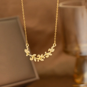 Close-up of golden laurel leaf pendant with sparkling white cubic zirconia on a delicate chain