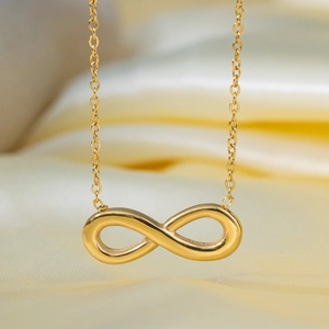 Collana con simbolo dell'infinito in oro lucido su sfondo di raso giallo