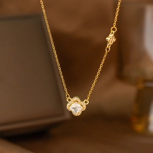Macro view of a gold clover pendant necklace with square crystal and laurel wreath detail