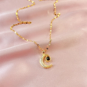 Elegant gold moon pendant necklace with micro-set diamonds on pink silk background