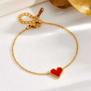 Close-up of golden stainless steel heart bracelet with red enamel and beaded border