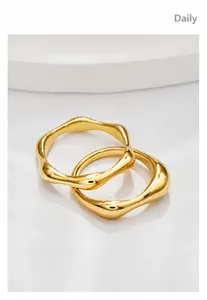 Macro detail of two minimalist 18k gold irregular wavy rings with polished finish