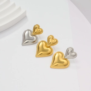 Detalle de pendientes de doble corazón en acabado dorado y plateado pulido