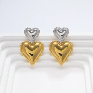 Primer plano de pendientes de corazón bicolor en oro de 18k sobre soporte blanco