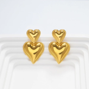 Detalle de los pendientes de corazón en oro de 18k con textura metálica de espejo