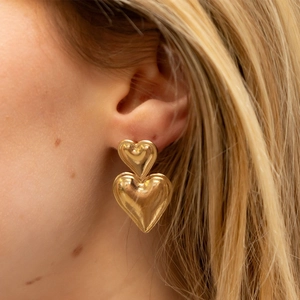 Elegantes pendientes de doble corazón en oro de 18k usados por una modelo real