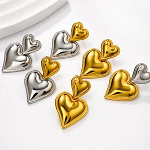 Detalle de los pendientes de corazón superpuestos en oro y plata sobre fondo blanco