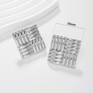 Macro detail of 30mm square stainless steel earrings with woven textured surface