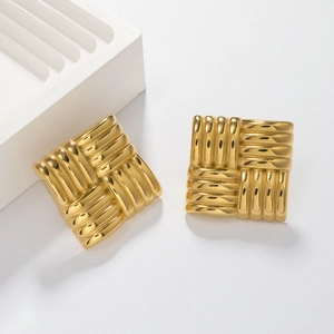 Macro shot of gold square stud earrings featuring intricate woven texture and metallic finish