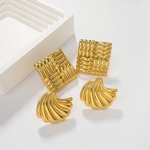 Close-up of golden square earrings featuring woven texture and radiant shell-shaped details