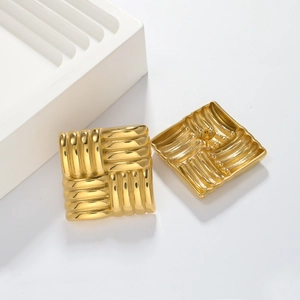 Close-up of golden square earrings featuring vertical ribbed texture and stud backing