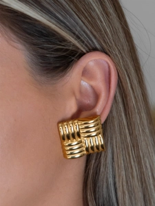 Macro shot of large gold square earrings with vintage ribbed texture on model ear