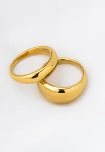 Close-up of two polished 18k gold plated stainless steel plain bands on white fabric